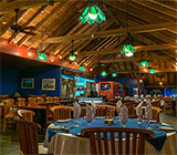 The dining room at the Restaurant at Leverick Bay with lofted, high-beam ceilings, overhead lighting, and tables set with linens and silverware.