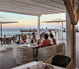 Four people dining on an outdoor patio at Nova restaurant in Virgin Gorda with the ocean in the background.