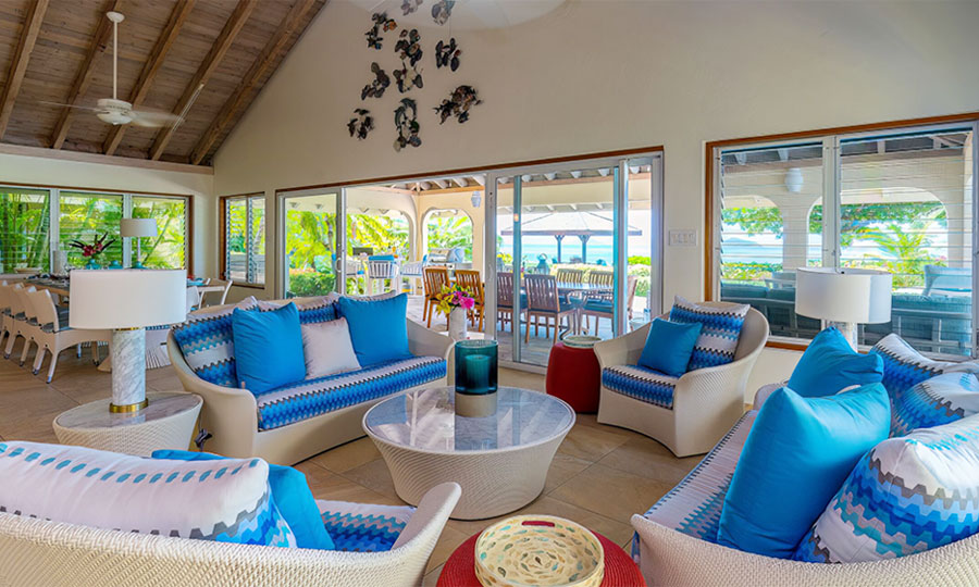 Beachcomber Villa great room with separate sitting and dining areas, colorful modern décor, and vaulted wood-beam ceilings.
