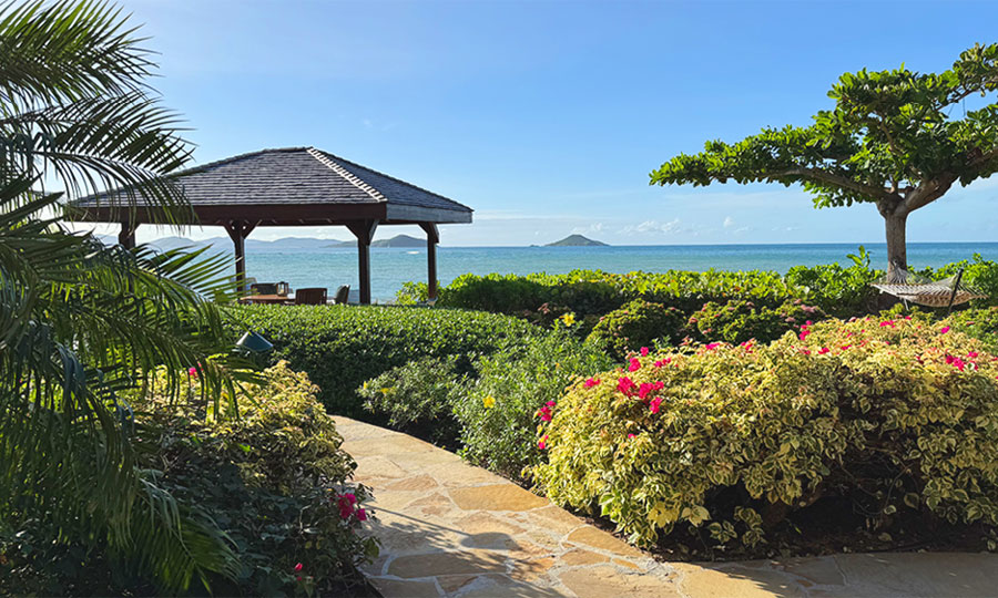 Beachcomber villa ocean view looking out on the tropical grounds and a beachfront gazebo with the waters of Mahoe Bay in the background.