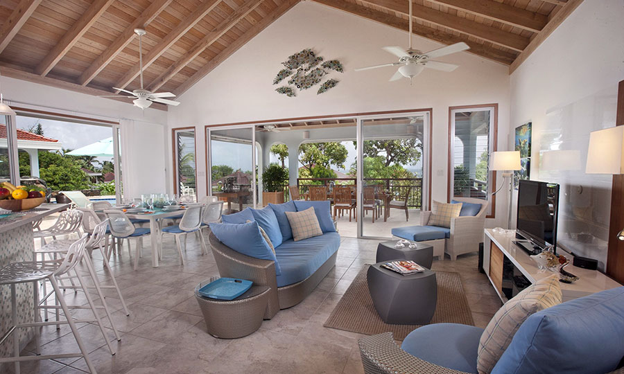 Bright main room at Blue Lagoon Villa with cool tile floors, a lofted wood ceiling  with fans, and spacious sitting and dining areas.